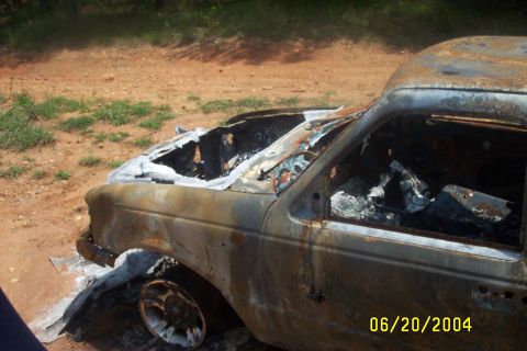 1979 Ford F-150 - A severely damaged truck sits in an outdoor setting, its interior and exterior heavily charred from a fire.
