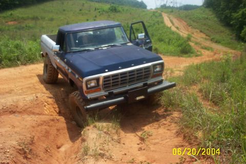 1979 Ford F-150 - A blue 1979 Ford F-150 navigates a challenging dirt path on a sunny day.