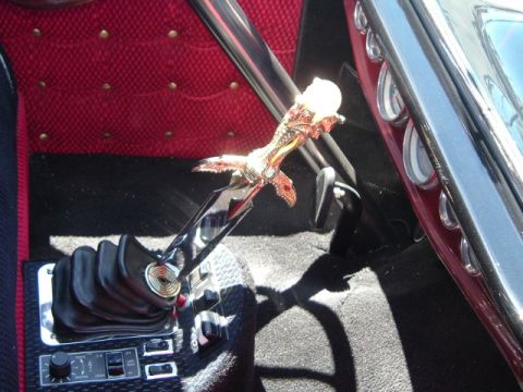 1989 Ford Bronco - A custom gear shifter with an eagle design is visible inside a vehicle, red diamond-stitched upholstery.