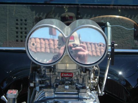 1989 Ford Bronco - Close-up of a vehicle's engine with dual carburetors and a blower, reflecting the surroundings.
