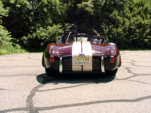 Rear view of burgundy Cobra roadster with cream stripes and 427ERA plate