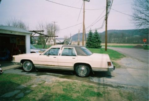 1987 Mercury Grand Marquis - This 1987 Mercury Grand Marquis sedan, a cream exterior and brown vinyl roof, is seen parked next to a garage.