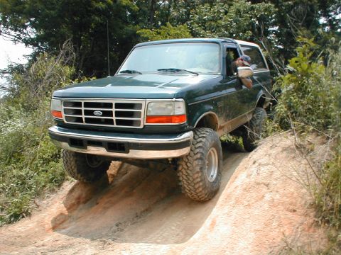 1995 Ford Bronco - This 1992 Ford Bronco is navigating a steep dirt incline with its large off-road tires.