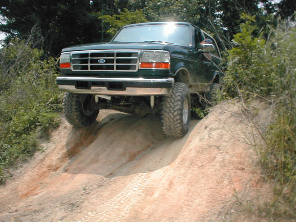 Green 1995 Ford Bronco climbing a dirt hill
