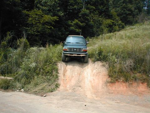 1995 Ford Bronco - 1995 Ford Bronco navigating an off-road trail on a sunny day.