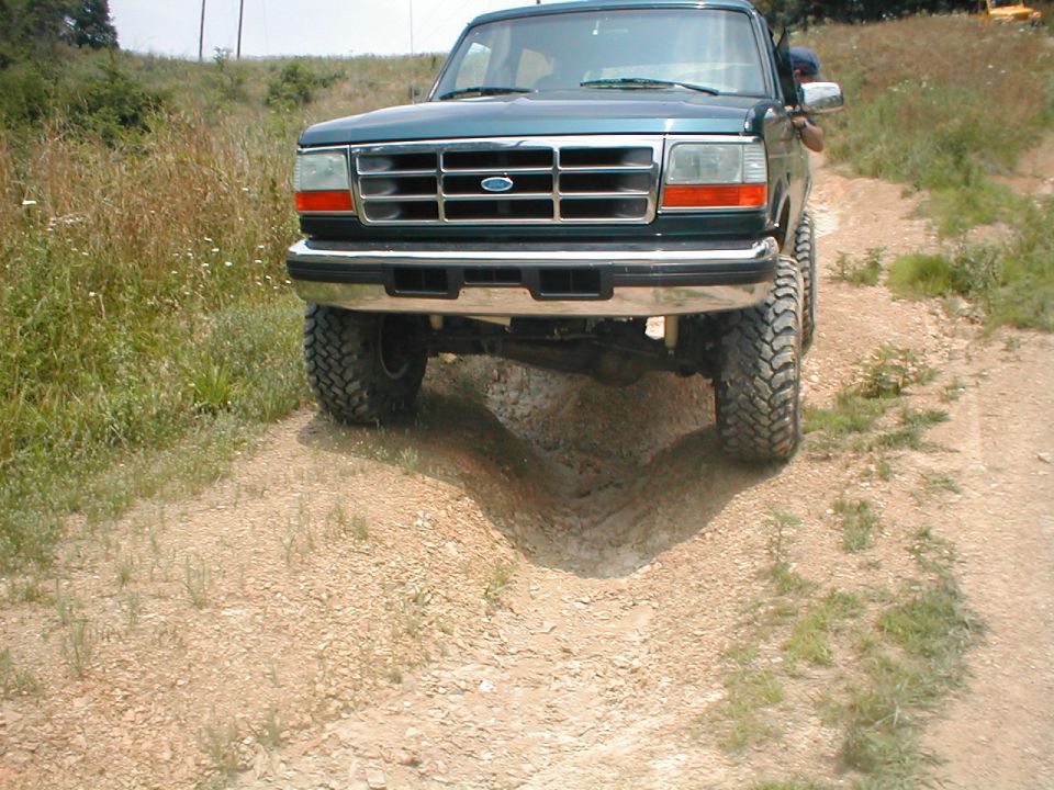 Green 1995 Ford Bronco on a dirt road, front view