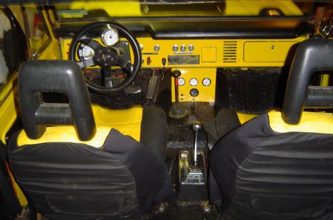 1974 Ford Bronco - The interior of a vehicle with yellow and black upholstery and a custom dashboard is visible.
