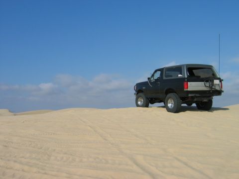 1985 Ford Bronco - 1985 Ford Bronco in sand dunes with a spare tire carrier on the rear.