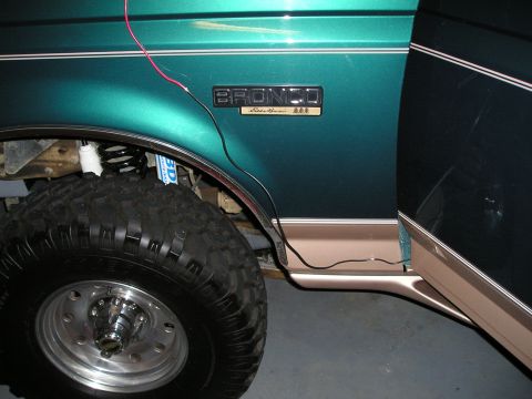 1996 Ford Bronco - Close-up of a green 1996 Ford Bronco's side, showing the "Eddie Bauer" trim and a large tire.