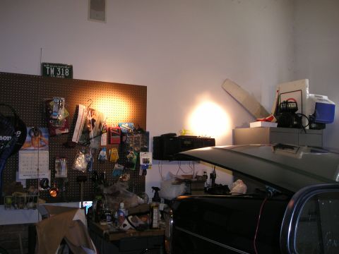 1996 Ford Bronco - A garage scene with a car's hood up, surrounded by tools, storage, and a license plate on the wall.