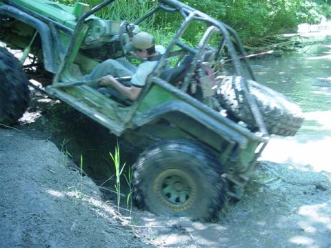 1992 Ford Bronco - This off-road vehicle navigates a challenging muddy terrain with water obstacles.