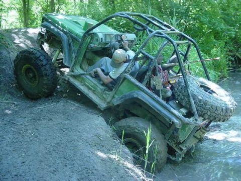 1992 Ford Bronco - An off-road vehicle navigates a challenging muddy and watery terrain.