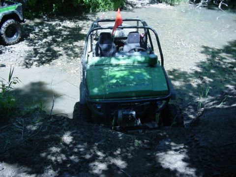 1992 Ford Bronco - A green off-road vehicle, possibly a Suzuki, is shown navigating a muddy stream with another vehicle visible in the background.
