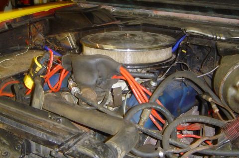 1974 Ford Bronco - Close-up view of an engine bay, orange spark plug wires and a large chrome air filter housing.