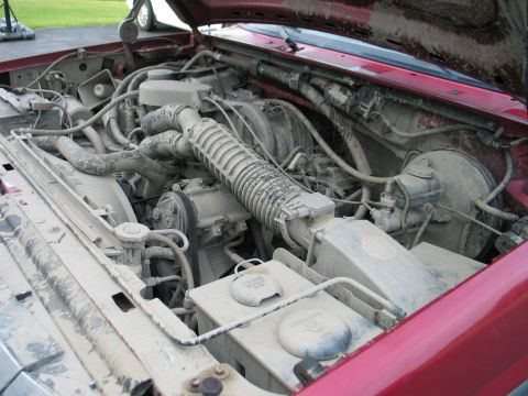 1995 Ford Bronco - The engine compartment is heavily coated in dust and dirt, obscuring many details.
