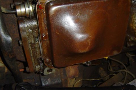 1974 Ford Bronco - Close-up view of a rusty oil pan, likely from an older vehicle.