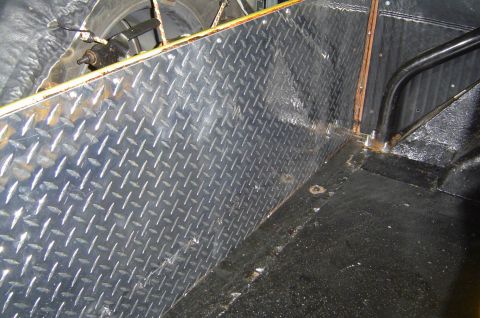 1974 Ford Bronco - The interior of a vehicle's cargo area features diamond plate lining and a black floor mat.