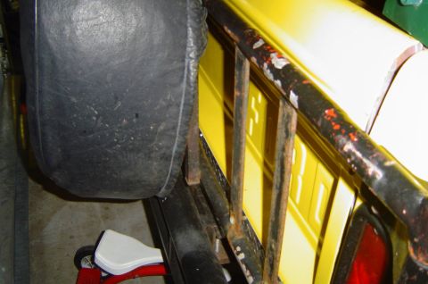 1974 Ford Bronco - Interior view of a yellow vehicle showing a spare tire and a child's seat.