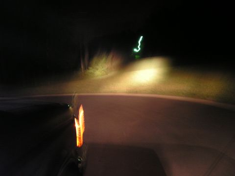 1996 Ford Bronco - Photo taken from inside a vehicle at night, showing the road ahead illuminated by headlights.