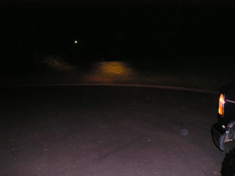 1996 Ford Bronco - Vehicle headlights illuminate a dark road at night.