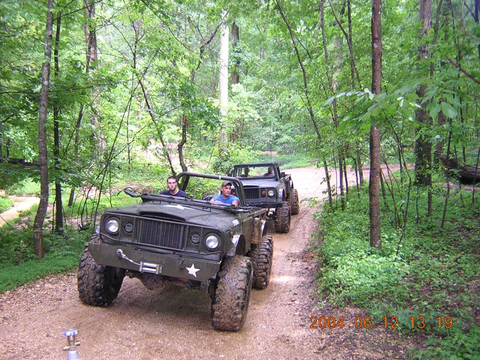 Olive green off-road vehicle with star emblem, front view. Two vehicles in line