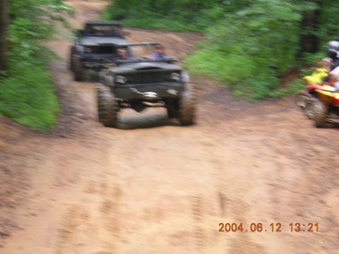 1984 Chevrolet Blazer - Multiple off-road vehicles navigate a muddy trail surrounded by lush green foliage.