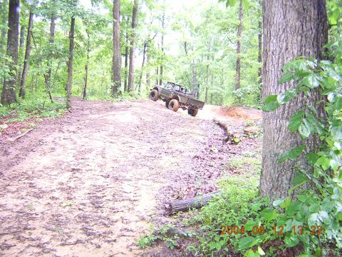 1984 Chevrolet Blazer - A truck navigates a challenging muddy trail in a wooded area.