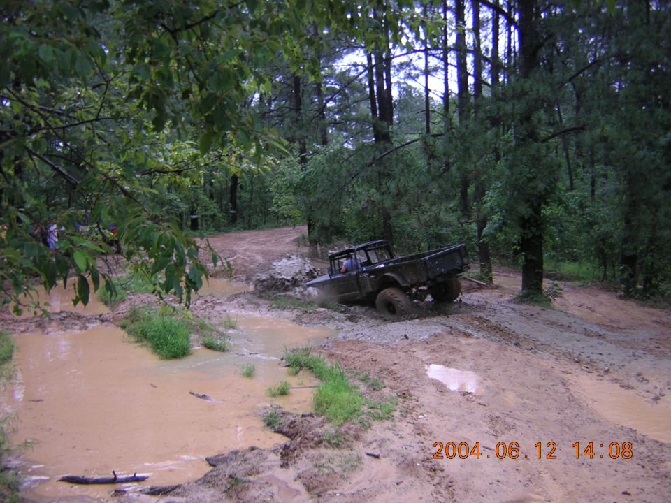 Dark off-road truck stuck in mud on a wooded trail