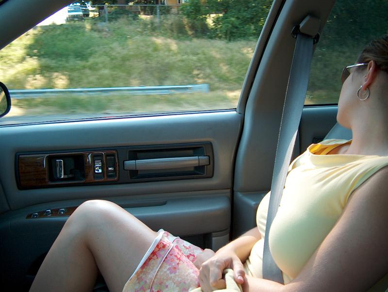 Car interior with beige door panel and passenger in yellow top wearing seatbelt