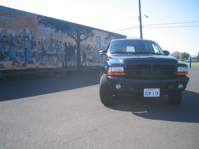 Dark blue Dodge Durango SUV parked in front of a painted mural on a brick wall.