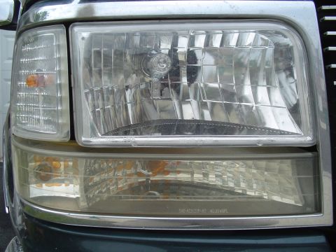 1993 Ford Bronco - Close-up of the front headlight and turn signal assembly on a 1993 Ford Bronco, chrome accents and clear lenses.