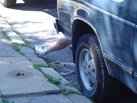 1993 Ford Bronco - Working on the exhaust system of a vehicle parked on the street.