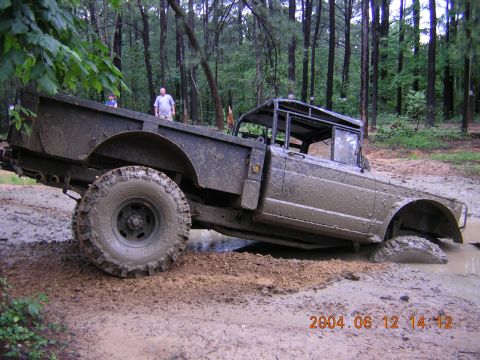 1984 Chevrolet Blazer - An off-road vehicle is stuck in a muddy terrain with trees in the background.