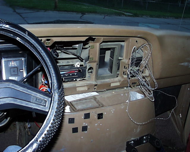 Tan van dash with radio bezel removed, head unit and loose wiring exposed