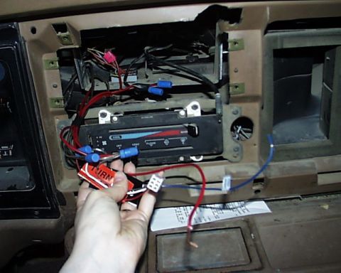 1988 Ford E250 - A hand holds wiring near the climate controls of a 1988 Ford E250's dashboard.