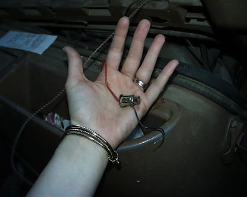 1988 Ford E250 - A hand holds a small electrical connector with wires, possibly for a vehicle repair.