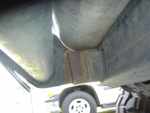 1993 Ford Bronco - Close-up view of a vehicle's undercarriage, revealing rusted components and a tire.