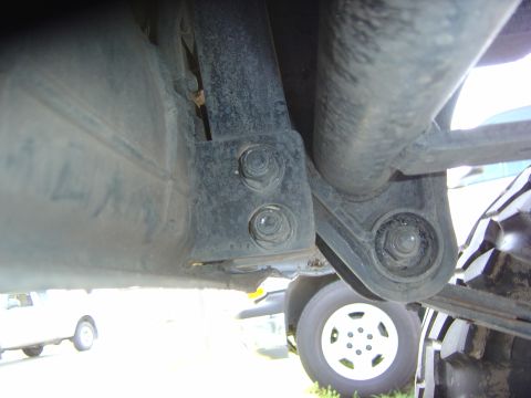 1993 Ford Bronco - Close-up of a vehicle's undercarriage, revealing suspension parts and a tire, with another vehicle partially visible in the background.