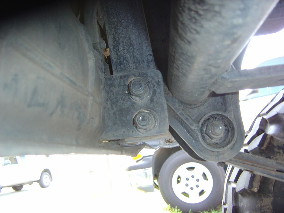Undercarriage view showing suspension and tire, with another vehicle in background