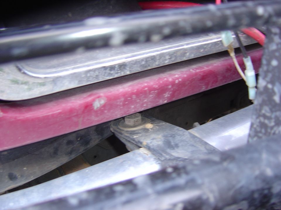 Close-up of vehicle undercarriage showing a red painted component and metal brackets