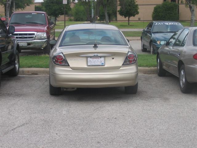 Gold sedan parked in a lot, rear view. License plate is visible