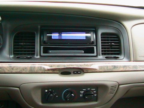 2000 Ford Crown Victoria - The interior of a 2000 Ford Crown Victoria shows its dashboard with an aftermarket stereo and climate controls.