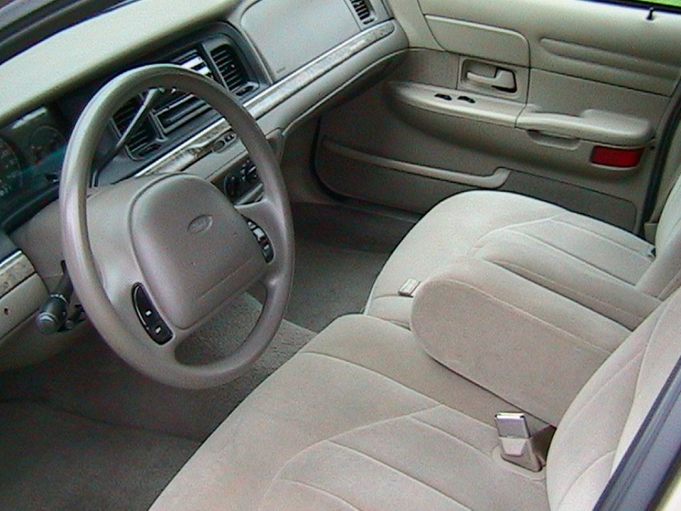 Tan cloth Ford sedan interior with airbag steering wheel and split-bench front seat