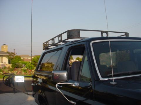 1988 Ford Bronco - 1988 Ford Bronco with aftermarket roof rack and spare tire carrier visible.
