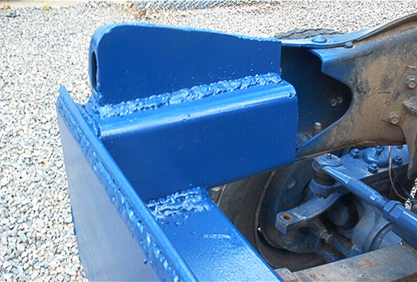 Freshly blue-painted frame bracket and crossmember of a vehicle chassis on gravel