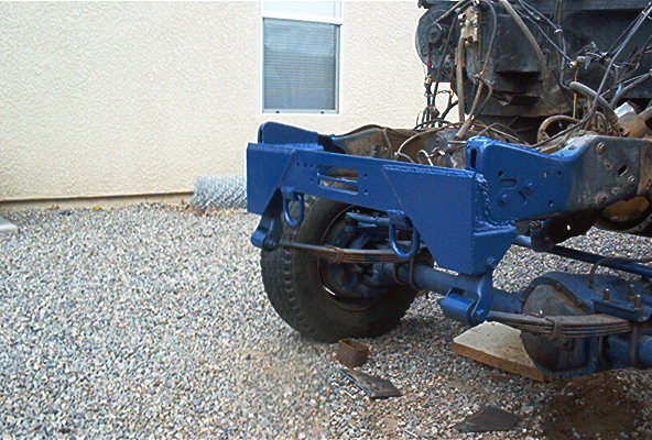 Blue-painted truck frame and leaf-spring rear suspension on gravel