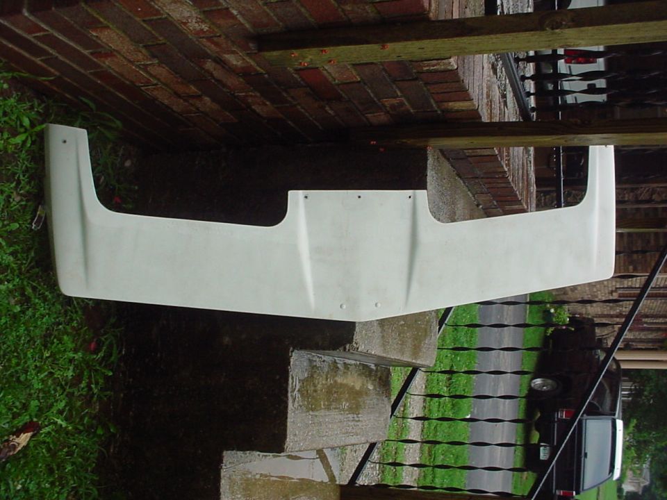 White fiberglass body panel with a wide, flat central section and angled ends, resting on concrete steps