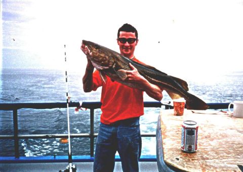 1994 Ford Bronco - A man proudly displays a large catch while on a boat, with a beverage nearby.