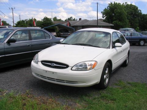2000 Honda Accord - A white Ford sedan is parked on a gravel lot next to another car under a cloudy sky.