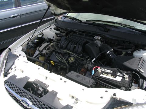 2000 Honda Accord - The engine bay of a white car is shown, with a Ford grille and a second vehicle in the background.
